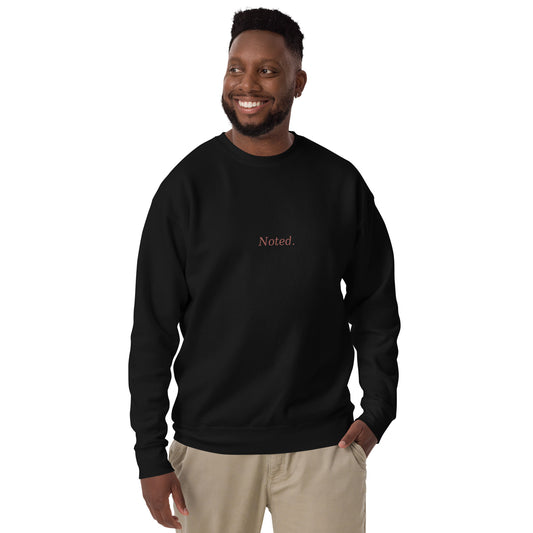 Man wearing a black sweatshirt with 'Noted' text on a white background